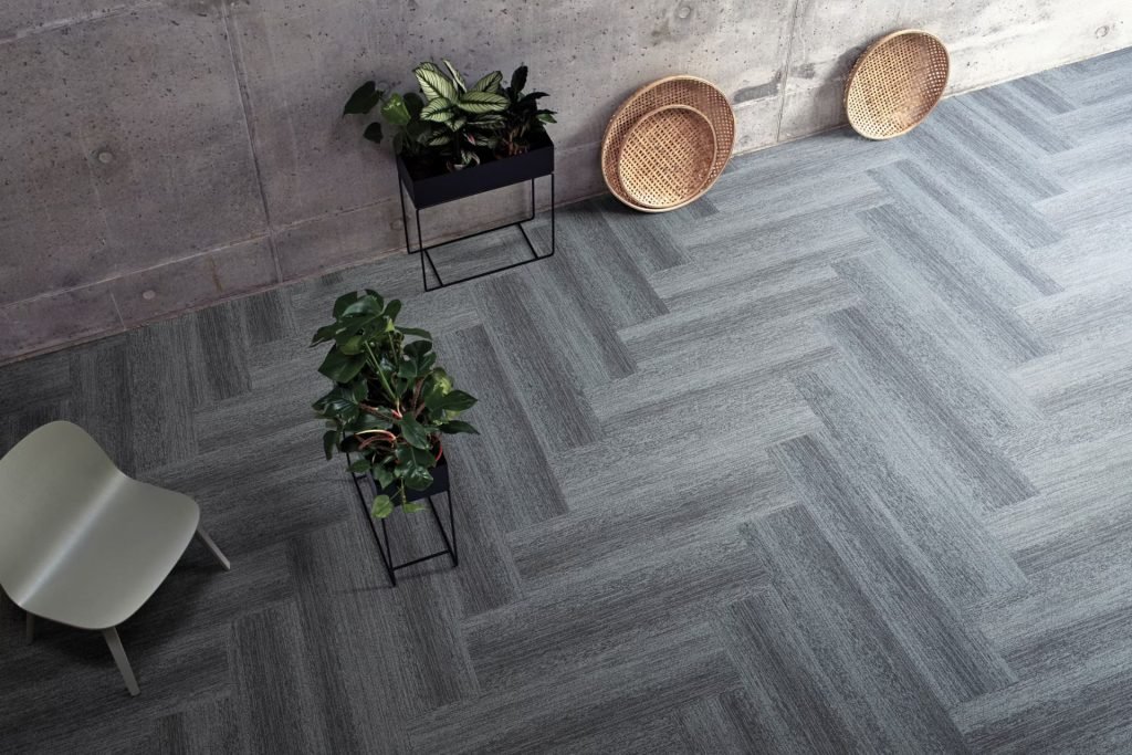 A room with grey tile flooring and a chair, representing carpet tile flooring services offered in Fresno, CA.