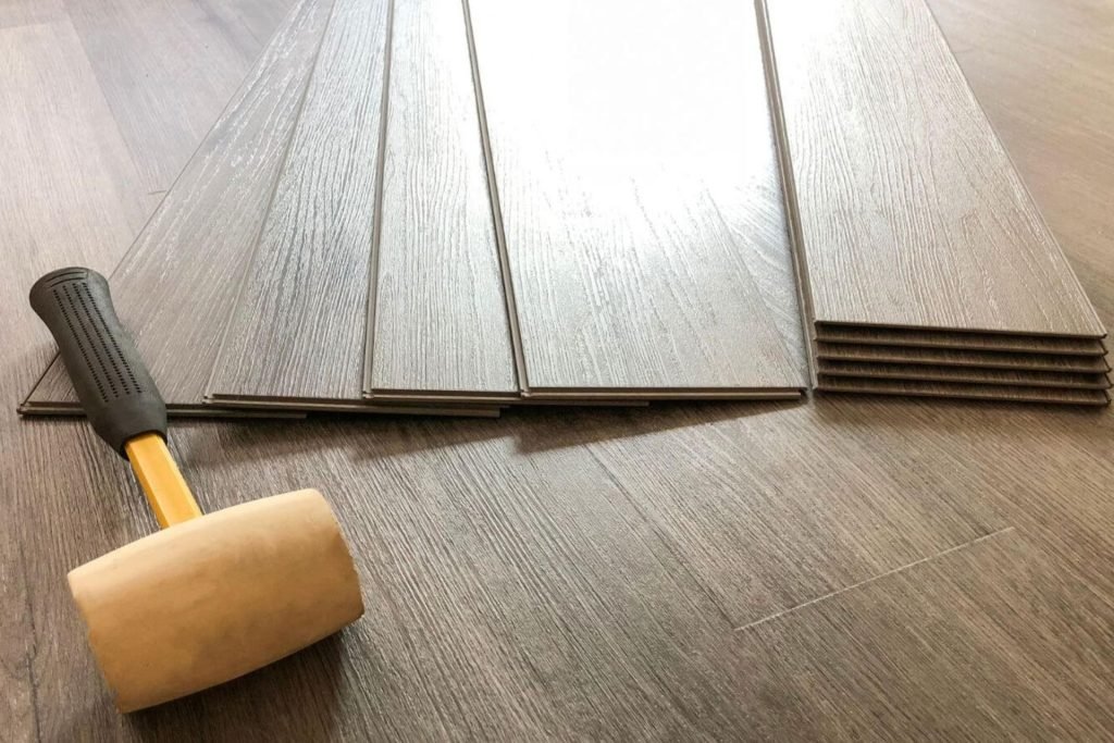 A person is engaged in installing laminate flooring, highlighting flooring services offered in Fresno, CA.